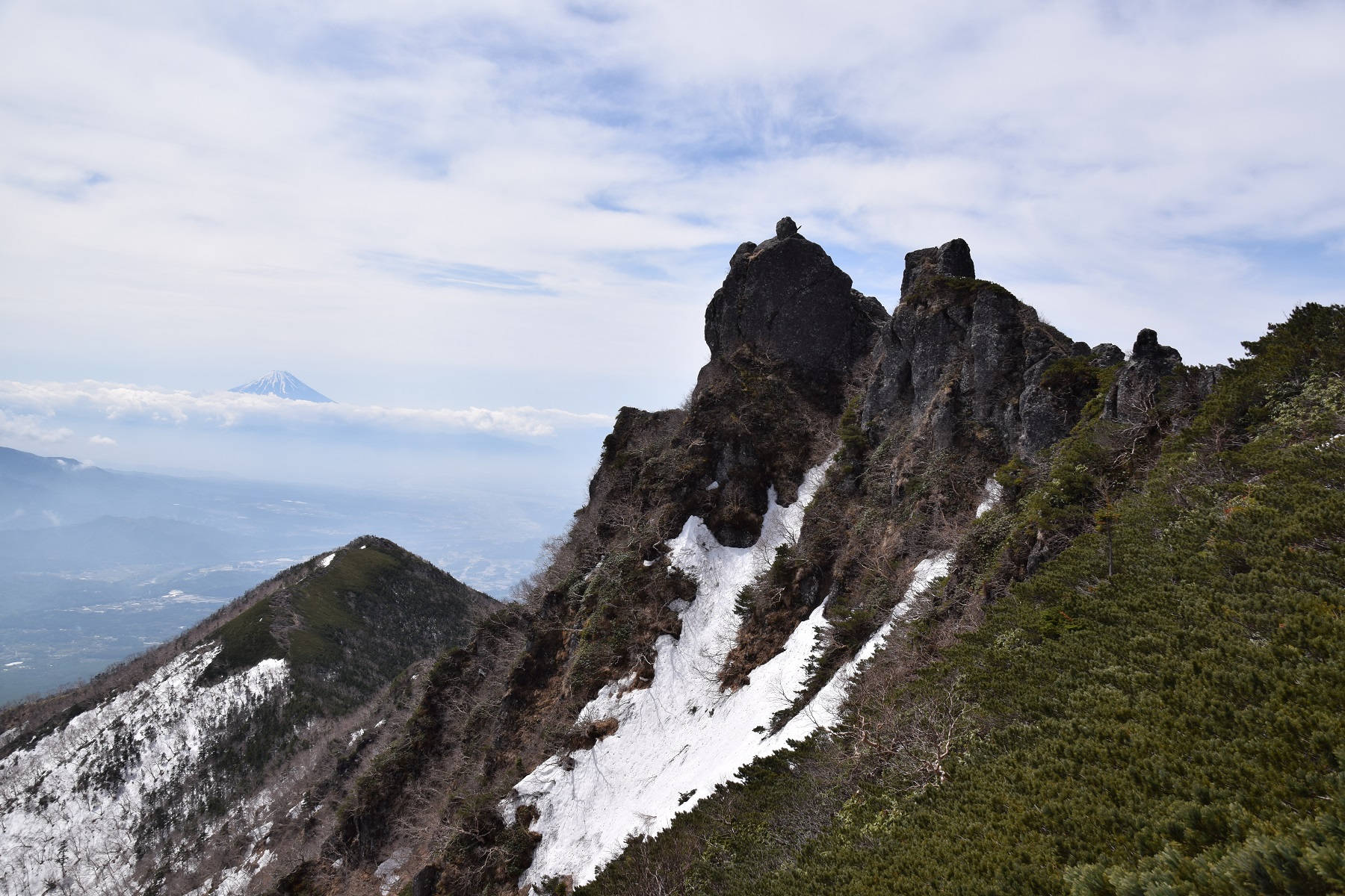 険しい権現岳山頂と左下に三ツ頭、その上に富士が見える