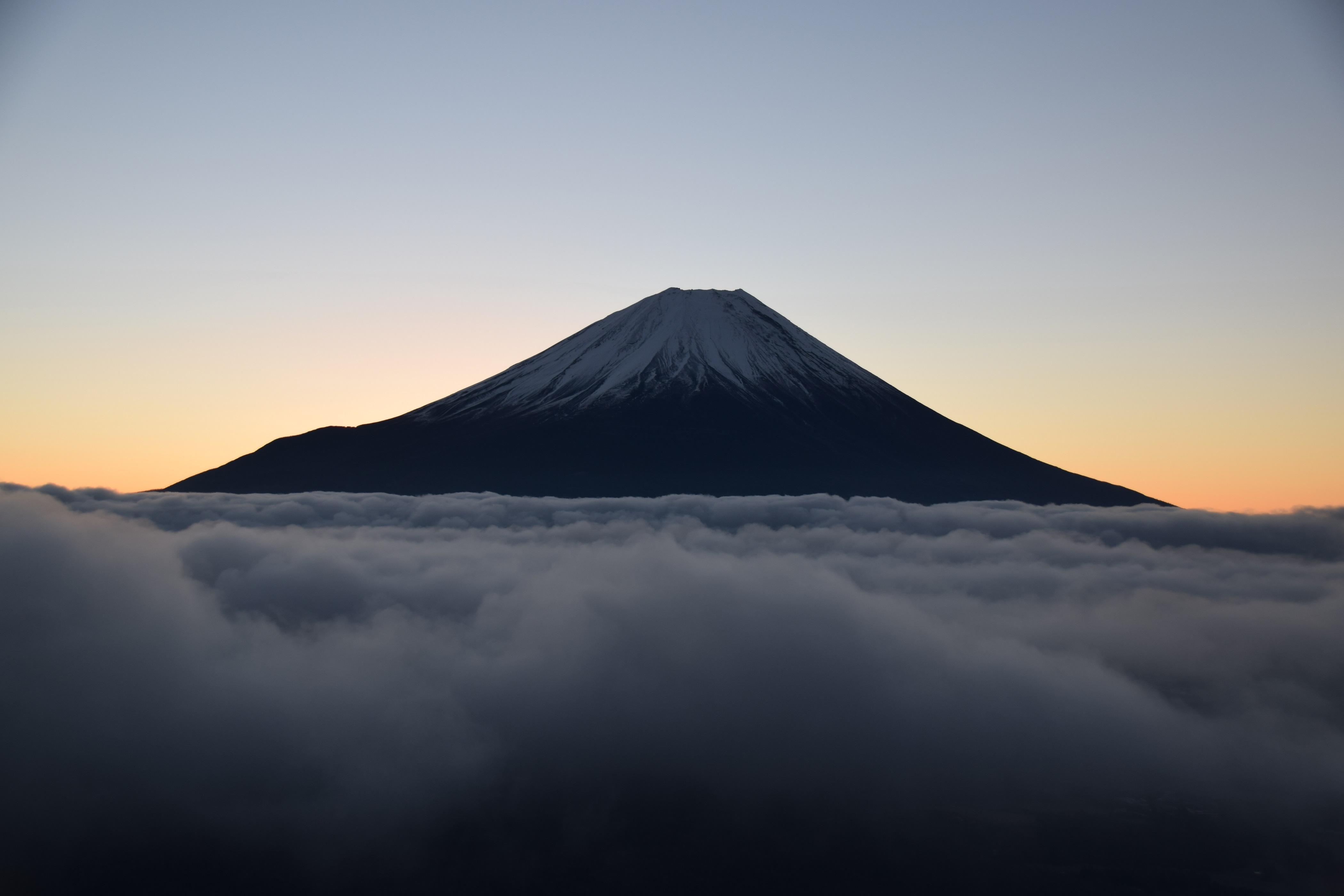 波立つ雲海に浮かぶ日の出前の富士
